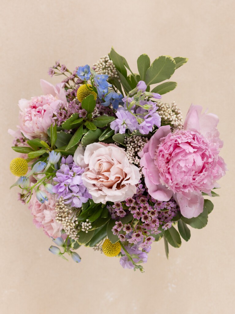 Top view of 23-stem Provence bouquet with peonies, blush roses, lavender stock, craspedia, and wildflower accents in a soft, garden-style mix.