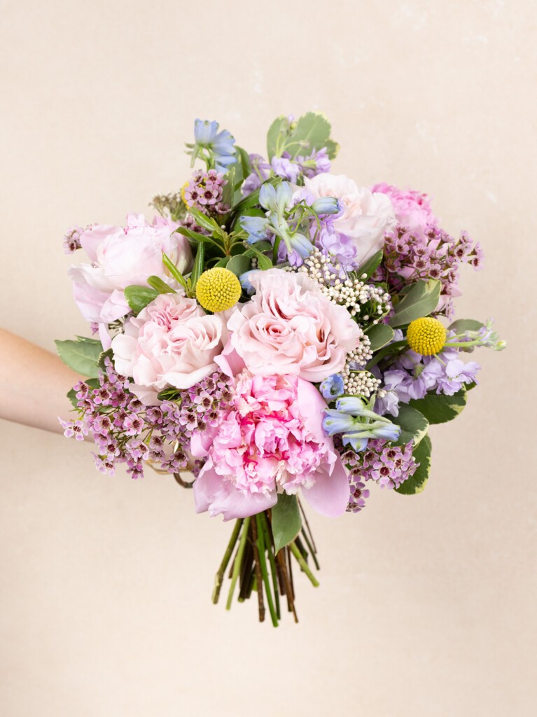 Hand-tied 23-stem bouquet with pink roses, peonies, lavender, craspedia, and wildflower accents, evoking a sunny day in the South of France.