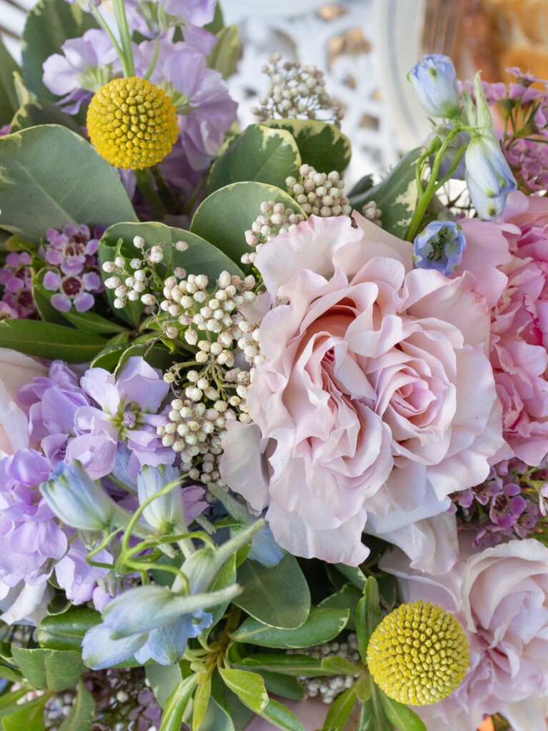 Close-up of 23-stem Provence bouquet with blush roses, lavender stock, craspedia, wax flower, and wild greenery in soft, textured summer tones.
