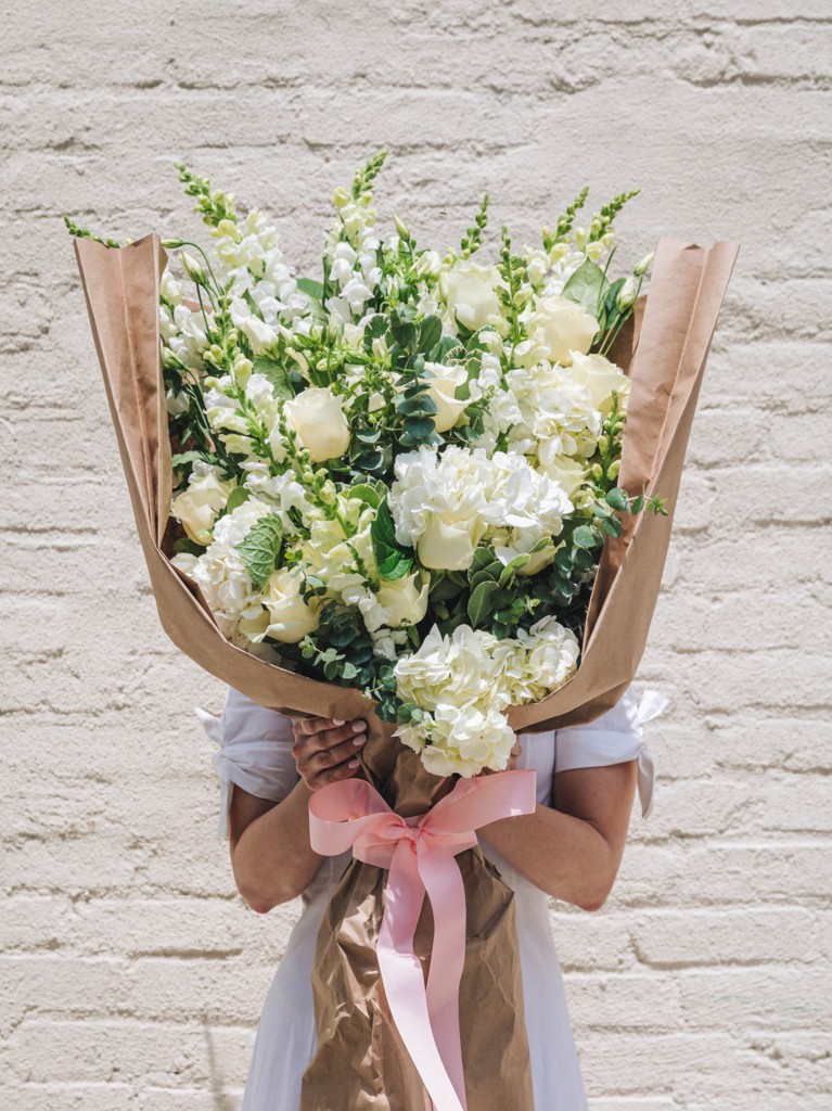 Front-facing view of the jumbo-sized Sabine bouquet, showcasing over 50 stems of seasonal white, cream, and green blooms wrapped in kraft paper and tied with ribbon, designed as a dramatic, 3-foot-tall statement piece.